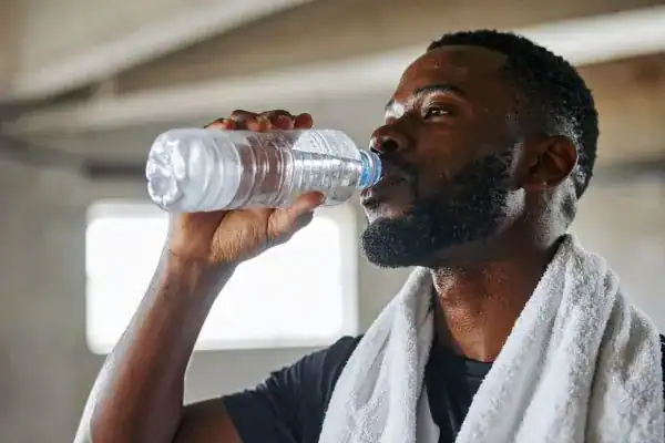 Image of man drinking water to improve hydration Herne Bay after work out.